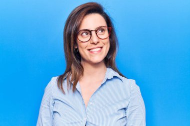 İş kıyafetleri ve gözlük takan genç ve güzel bir kadın. Taraf arıyor, rahat profil pozu veriyor. Doğal bir yüzü ve kendine güvenen bir gülümsemesi var.. 