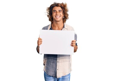 Genç İspanyol adam boş pankart tutuyor. Olumlu ve mutlu görünüyor. Kendine güvenen bir gülümsemeyle dişlerini gösteriyor. 