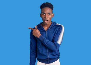 Spor giyimli genç Afro-Amerikan adam şaşırdı. Parmakla işaret etti, ağzı açık hayret içinde kaldı.. 