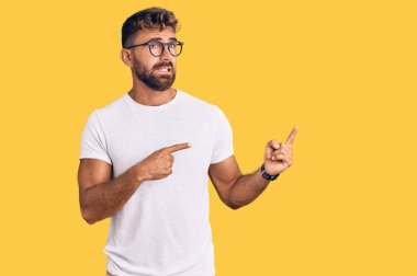 Gündelik kıyafet ve gözlük takan genç İspanyol bir adam iki eliyle endişeli ve gergin, endişeli ve şaşırmış ifadesini işaret ediyor. 