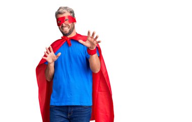 Sarışın, süper kahraman kıyafeti giyen, tiksindirici bir ifade takınan, tiksindirici bir yüz ifadesi takınan, tiksindirici bir yüz ifadesi olan genç bir adam. Eller havada. 