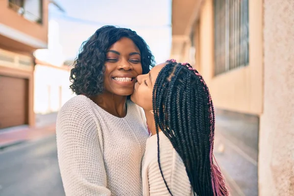 美しいアフリカ系アメリカ人の母親と娘の笑顔と抱擁 街でキスをしながら笑顔で立って — ストック写真