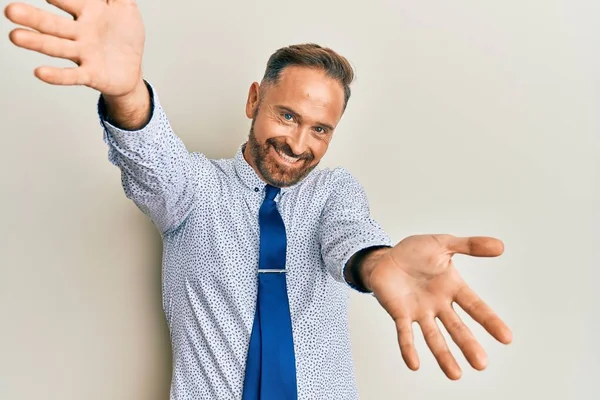 ビジネスシャツを着たハンサムな中年男性と抱擁のための開いた腕で笑みを浮かべてカメラを見てネクタイ 幸せを受け入れる陽気な表情 — ストック写真