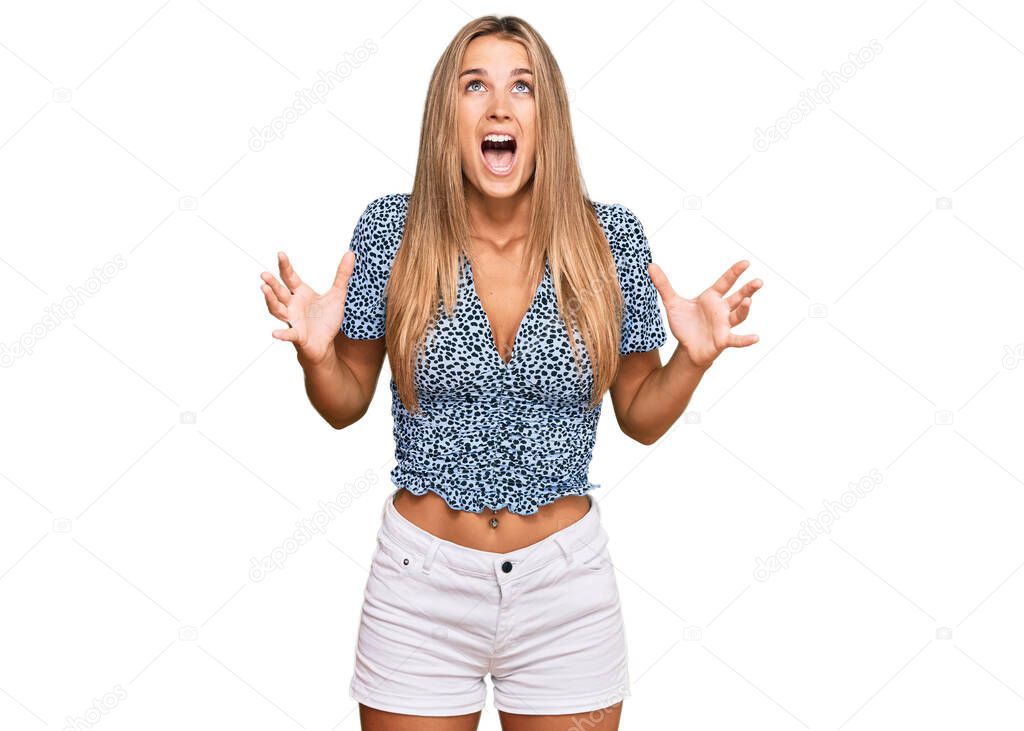 Young blonde woman wearing casual clothes crazy and mad shouting and yelling with aggressive expression and arms raised. frustration concept. 