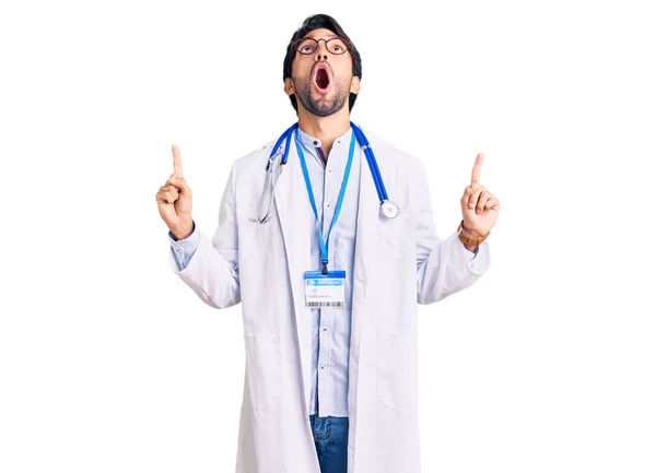 Przystojny Hiszpan Noszący Mundur Lekarza Stetoskop Zdumiony Zaskoczony Patrząc Górę — Zdjęcie stockowe