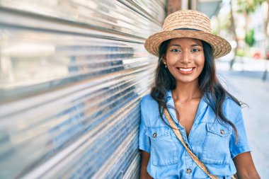 Genç, güzel Hintli bir kadın duvara yaslanıyor ve gülümsüyor..