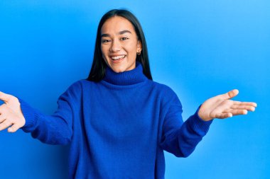 Genç Asyalı kadın, günlük kışlık süveter giyiyor. Gülümsüyor, yardım eli uzatıyor ve kabul ediyor.. 