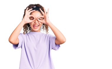 Kıvırcık saçlı güzel bir kız. Günlük kıyafetler giyiyor. Dürbün gibi jest yapıyor. çılgın ifade. 