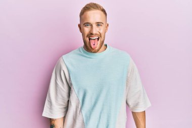 Günlük kıyafetler giyen genç beyaz bir adam komik bir ifadeyle dilini dışarı çıkartıyor. duygu kavramı. 