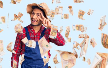 Yakışıklı Latin Amerikalı, tamirci üniforması giyen, barış sembolü çizen, gülümseyen, zaferi gösteren genç adam.