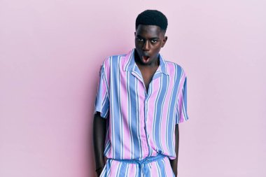 Şok olmuş gibi giyinmiş, kuşkucu ve iğneleyici bakışları olan, ağzı açık kalmış genç Afro-Amerikan bir adam. 