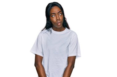 Gündelik beyaz tişört giyen genç Afro-Amerikalı bir kadın dudaklarıyla balık suratı yapıyor, çılgınca ve komik bir jest. Komik ifade. 