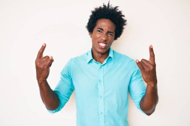 Yakışıklı Afro saçlı, sıradan giyinmiş çılgın bir ifadeyle bağıran elleri havada rock sembolü yapan Afro-Amerikan bir adam. Müzik yıldızı. ağır kavram. 