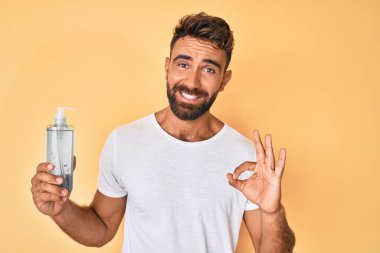 Genç İspanyol adam el dezenfektanı kullanıyor. Parmaklarıyla imza atıyor. Gülümsüyor. 