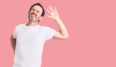 Orta yaşlı yakışıklı bir adam gündelik tişörtler giyiyor. Yorgun ve rahat, uykulu ve sabahın erken saatleri için esniyor. 