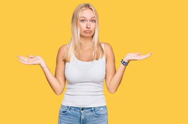 Kolsuz tişörtlü, sıradan giyinen genç sarışın kız. Hiçbir fikri olmayan, kolları açık ve kafası karışık bir kız.. 