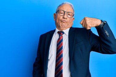 Beyaz adam iş elbisesi giymiş ve kravat takmış. Kol kası gösteren güçlü biri. Kendinden emin ve gururlu. 