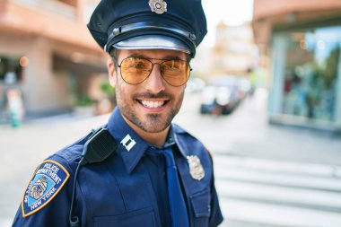 Polis üniforması giyen genç, yakışıklı İspanyol polis mutlu bir şekilde gülümsüyor..