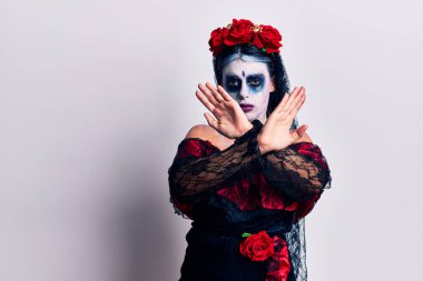 Ölü makyajlı bir Meksika günü giymiş genç bir kadın. Reddedilmiş yüz ifadesi. Kollarını kavuşturup negatif işaret veriyor. 