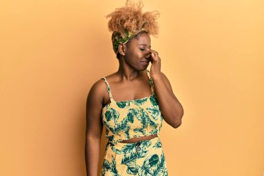 Afro saçlı, yaz elbisesi giyen genç bir Afrikalı kadın pis ve iğrenç bir koku alıyor, dayanılmaz bir koku, parmakları burnunda nefesini tutuyor. Kötü kokuyor. 