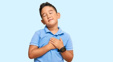 Sıradan kıyafetler giyen, göğsünde elleri kapalı, yüzünde minnet dolu bir jestle gülümseyen İspanyol çocuk. sağlık kavramı. 