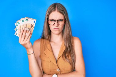 Avro banknotları tutan genç sarışın kız şüpheci ve gergin, sorun yüzünden surat asıyor. negatif kişi. 