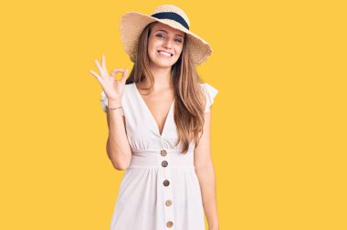 Yazlık elbise ve şapka giyen, gülümseyen genç, güzel sarışın kadın el ve parmaklarıyla 