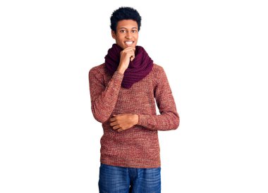 Sıradan bir kazak ve eşarp giyen Afro-Amerikan genç adam kameraya kollarını kavuşturmuş ve çenesini kaldırarak gülümsüyor. Olumlu düşünmek. 