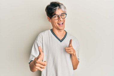 Gündelik kıyafetler giyen ve gözlüklü genç İspanyol adam mutlu ve komik yüzlü parmaklarını kameraya doğrultuyor. iyi enerji ve titreşimler. 