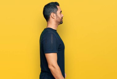 Latin kökenli genç adam rahat bir görünüm takınıyor, rahat bir görünüm takınıyor, kendine güvenen bir gülümsemeyle.. 