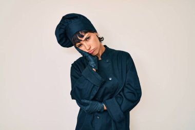 Profesyonel aşçı üniforması giyen güzel esmer kadın kollarını kavuşturarak depresyondan sıkılmış ve yorgun göründüğünü düşünüyor.. 