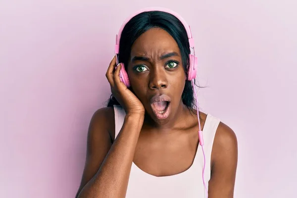 Young African American Woman Listening Music Using Headphones Scared Amazed — Stock Photo, Image