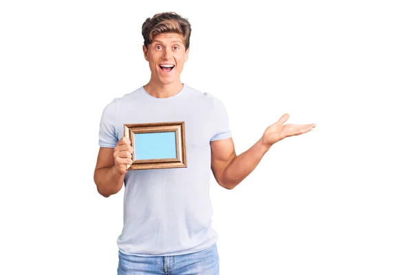 Young Handsome Man Holding Empty Frame Celebrating Victory Happy Smile — 图库照片
