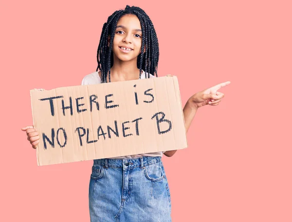 Cute african american girl holding there is no planet b banner smiling happy pointing with hand and finger to the side