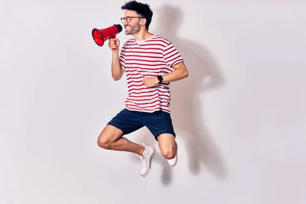 Young Handsome Hispanic Man Wearing Glasses Screaming Using Megaphone Jumping — Stock Photo, Image