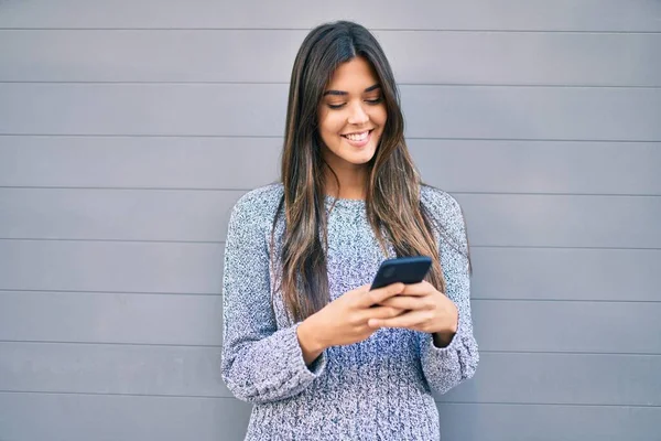 若いです美しいですヒスパニック系の女の子笑顔幸せな使用してスマートフォンで市 — ストック写真