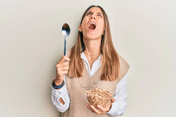 Mujer Joven Morena Comiendo Cereales Integrales Saludables Con Cuchara Enojada — Foto de Stock