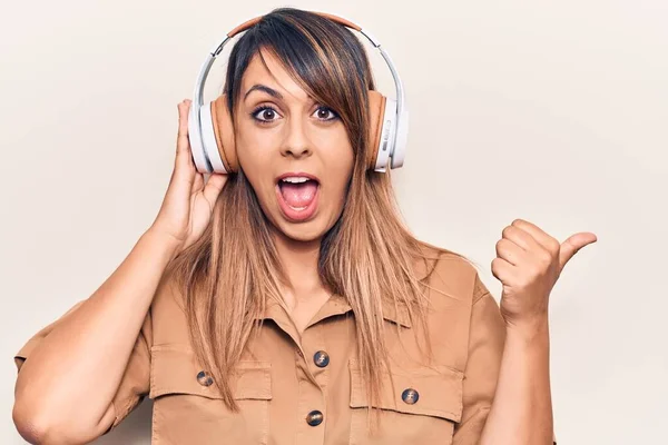 Joven Hermosa Mujer Escuchando Música Usando Auriculares Apuntando Pulgar Hacia —  Fotos de Stock