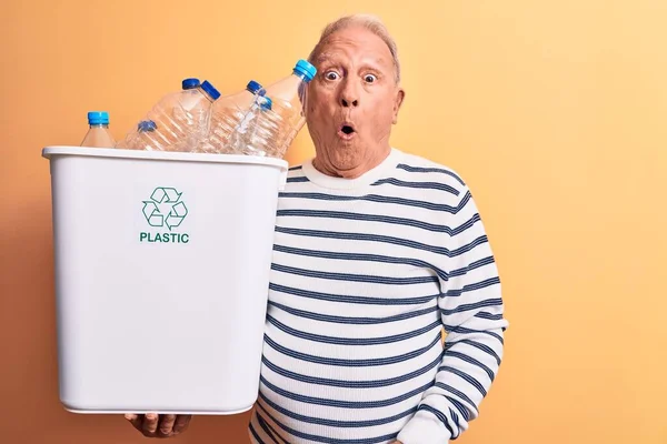 シニアハンサムな白髪の男は プラスチックボトルの恐怖と驚きのために口を開けて驚いて 不信顔の完全な財布を保持リサイクル — ストック写真