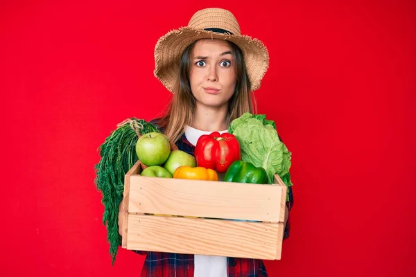 漂亮的高加索女人头戴农民帽 头戴蔬菜 持怀疑和紧张的态度 因问题皱着眉头 消极的人 — 图库照片