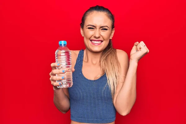 Joven Hermosa Mujer Rubia Bebiendo Botella Agua Sobre Fondo Rojo —  Fotos de Stock