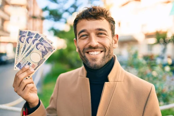エレガントなジャケットを着たハンサムなビジネスマンが屋外で幸せな笑顔を見せ 5000円の紙幣を見せます — ストック写真