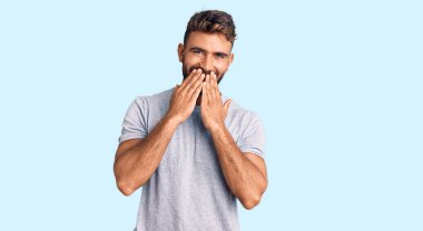 Günlük kıyafetler giyen genç İspanyol adam gülüyor ve utanıyor kıkır kıkır kıkır gülüyor elleriyle ağzını kapatıyor, dedikodu ve skandal konsepti. 