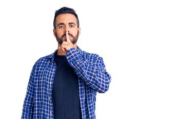 Gündelik kıyafetler giyen genç İspanyol adam parmakları dudaklarında sessiz olmak istiyor. sessizlik ve gizli konsept. 