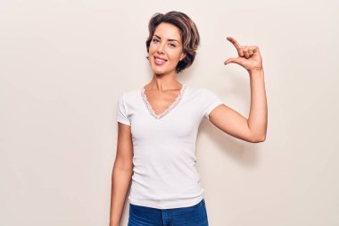 Gündelik kıyafetler giyen, gülümseyen, kendine güvenen, el hareketleriyle küçük beden işareti yapan, parmaklarını gösterip kameraya bakan genç ve güzel bir kadın. ölçüm kavramı. 