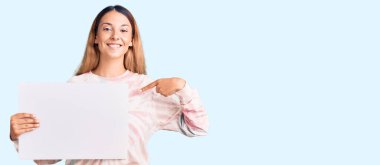 Boş pankart tutan güzel genç bir kadın mutlu ve gururlu bir kendini işaret ediyor. 