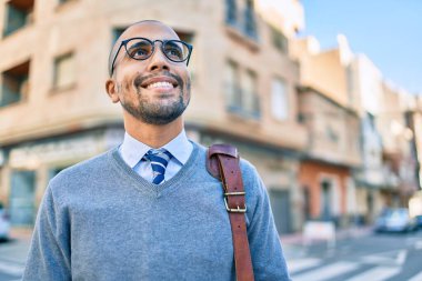 Genç Afrikalı Amerikalı iş adamı gülümseyerek şehirde mutlu bir şekilde yürüyor..
