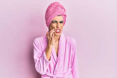 Kadın elbisesi giyen genç adam, diş ağrısı ya da diş ağrısı yüzünden duş havlusu ve bornozla ağıza dokunuyor. dişçi 