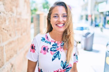 Genç İspanyol kadın gülümseyerek şehirde mutlu mesut duruyor.