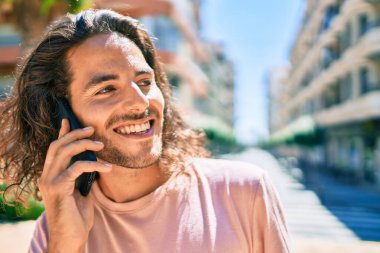 Genç İspanyol adam gülümsüyor. Şehirdeki akıllı telefondan konuşuyor..